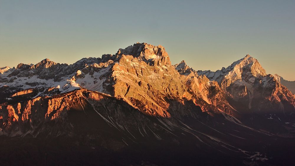 Tall mountain peaks and crests illuminated by the setting sun. Original public domain image from Wikimedia Commons