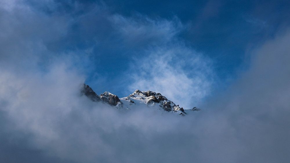 Wispy clouds frame a snowy mountain's crest in San Pellegrino Pass. Original public domain image from Wikimedia Commons