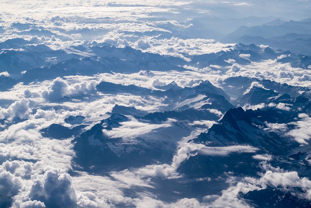 An aerial shot of sharp mountain ridges emerging from a sea of clouds. Original public domain image from Wikimedia Commons