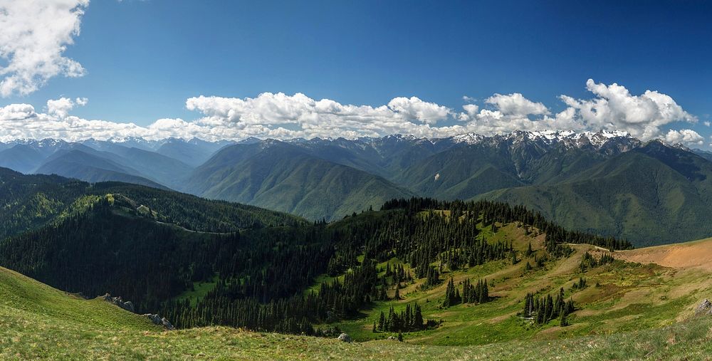 Green mountains with snow-topped crests under fluffy clouds. Original public domain image from Wikimedia Commons