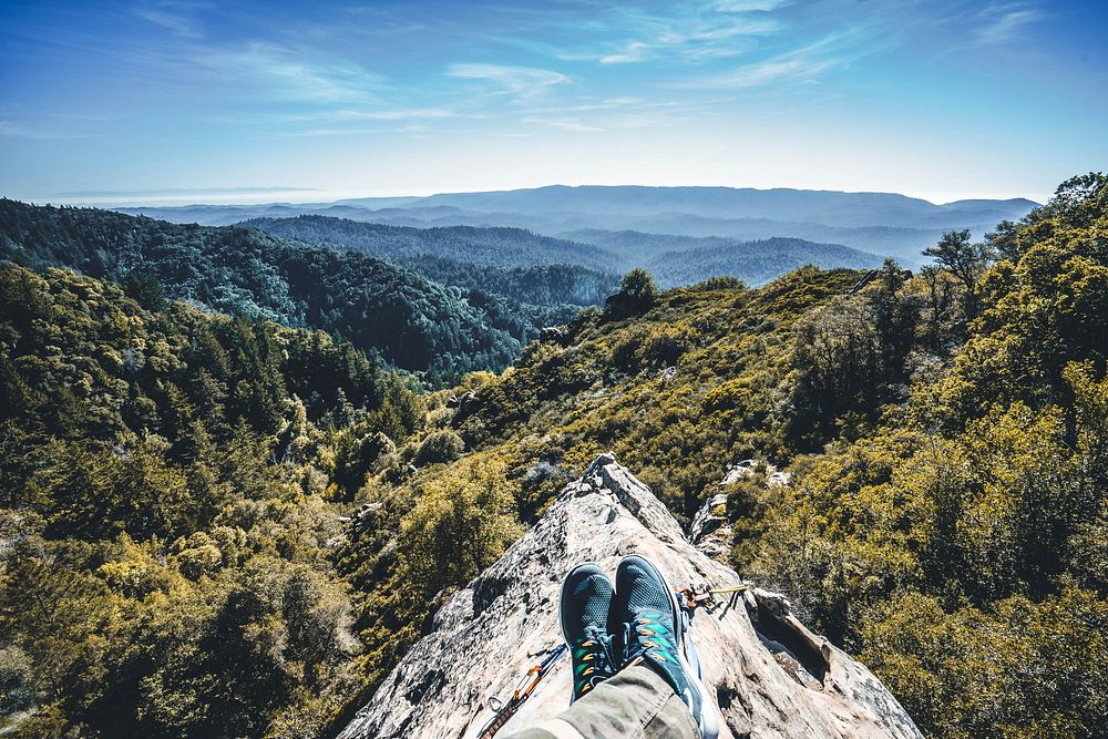 A mountaineer's outstretched legs on a rocky ridge. Original public domain image from Wikimedia Commons