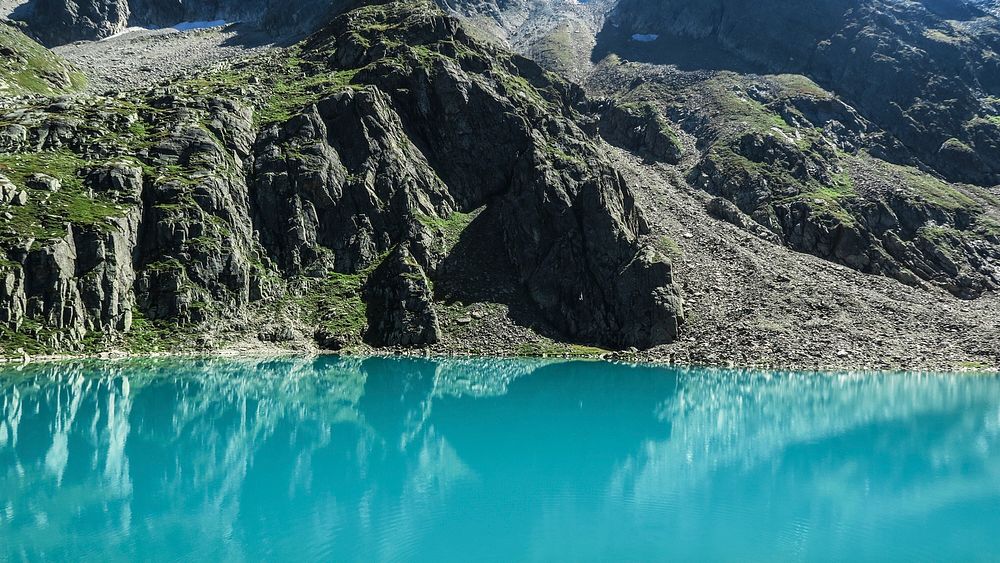 An aquamarine lake beside a mossy mountain. Original public domain image from Wikimedia Commons