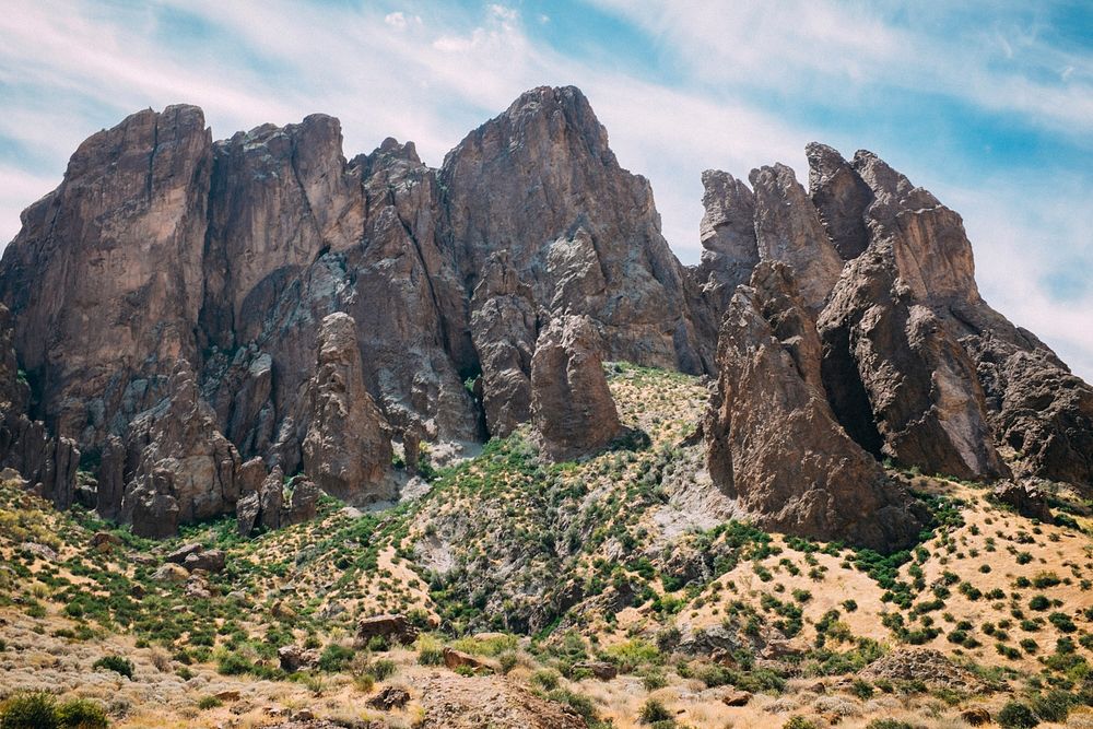 Rock formations stand tall among desert foliage on a hot day. Original public domain image from Wikimedia Commons