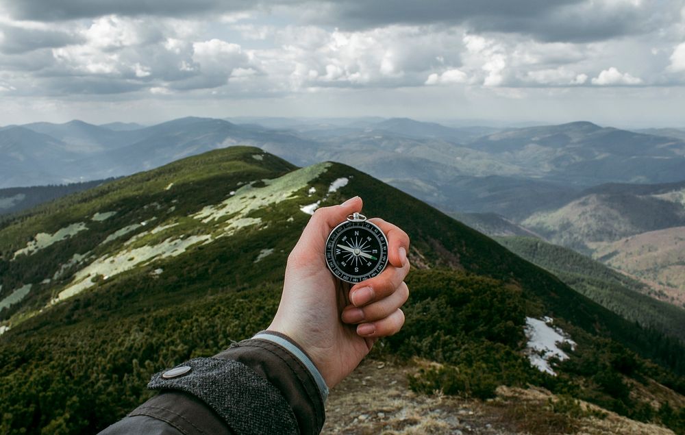 A person holding a compass while standing on a ridge in the Carpathian Mountains. Original public domain image from…