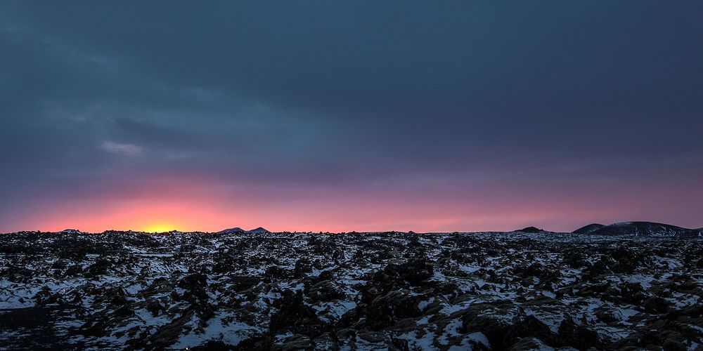 The sun just below horizon on a rocky landscape with light snow. Original public domain image from Wikimedia Commons