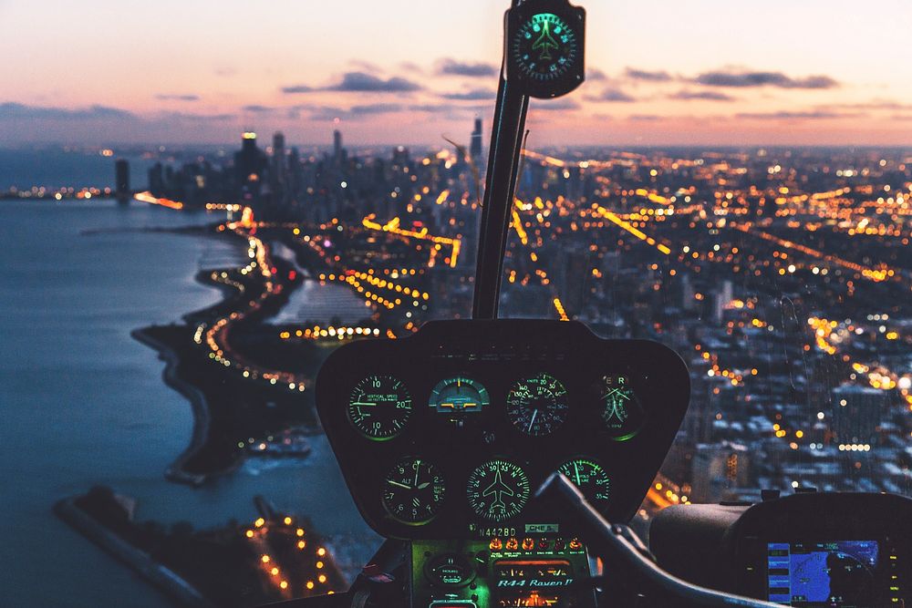 Dashboard of helicopter flying over a city with skyscrapers at dusk. Original public domain image from Wikimedia Commons