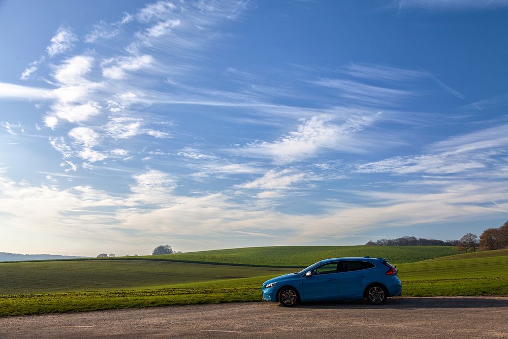 Blue car parked along field under blue sky. Original public domain image from Wikimedia Commons