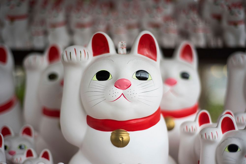 A number of Japanese maneki-neko figurines depicting a beckoning white cat. Original public domain image from Wikimedia…