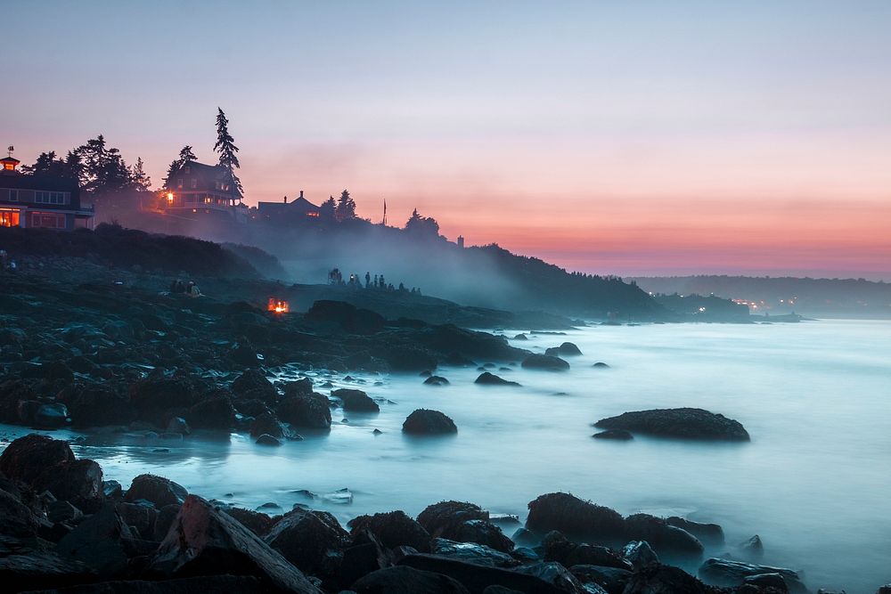Sunset on a rocky coastline of Ogunquit where groups of people are watching an ocean mist rising from the waters. Original…