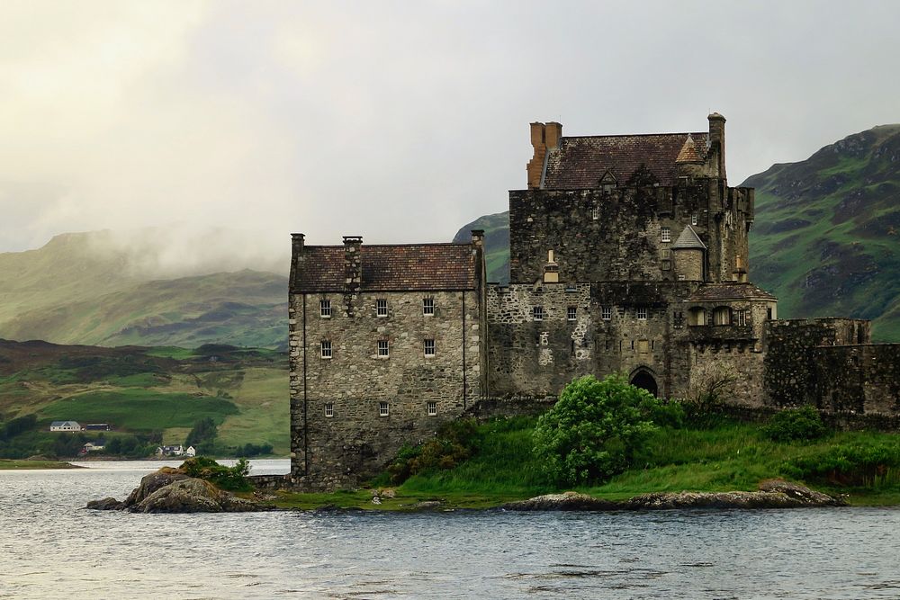Historic Eilean Donan Castle on grassy shores by the water. Original public domain image from Wikimedia Commons