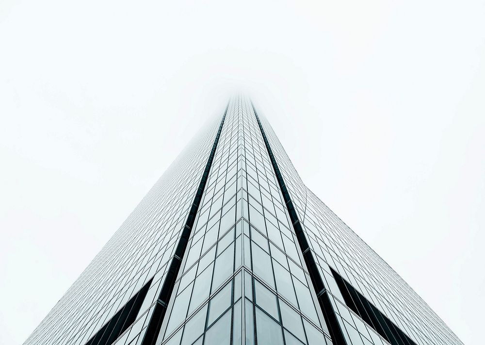Fog covers the top of a tall building with rectangular glass design facade in Madrid.. Original public domain image from…