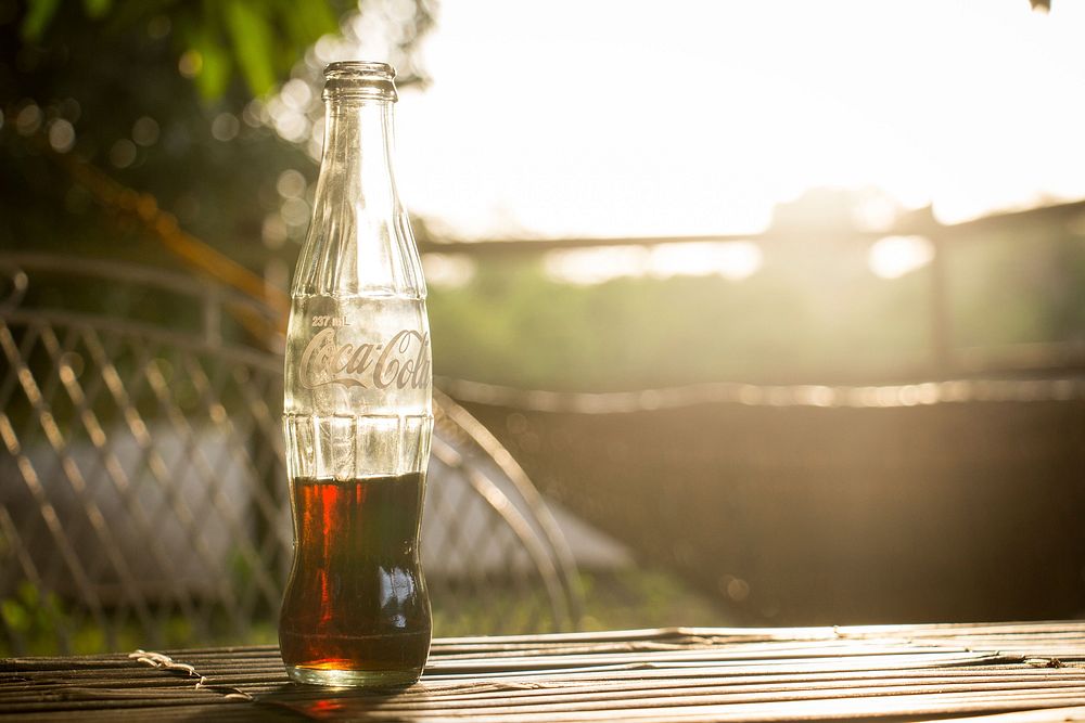 Coca Cola bottle on a table. Original public domain image from Wikimedia Commons