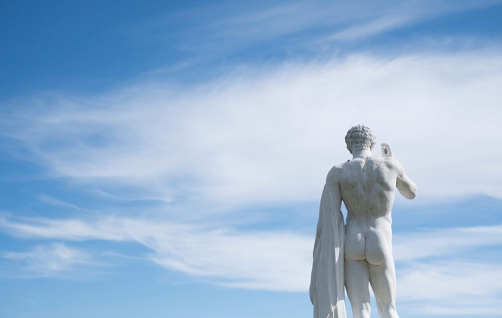 Back of a nude art statue at a museum against a blue cloudy sky. Original public domain image from Wikimedia Commons