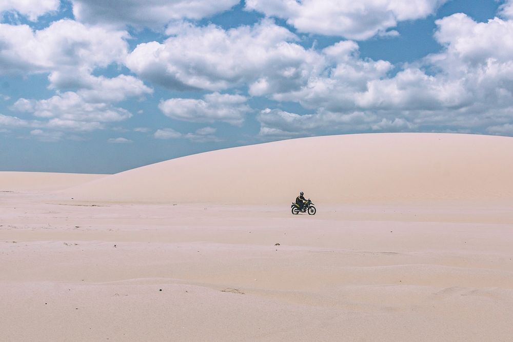 Dirt biker rides alone through the white sand desert Dunes. Original public domain image from Wikimedia Commons