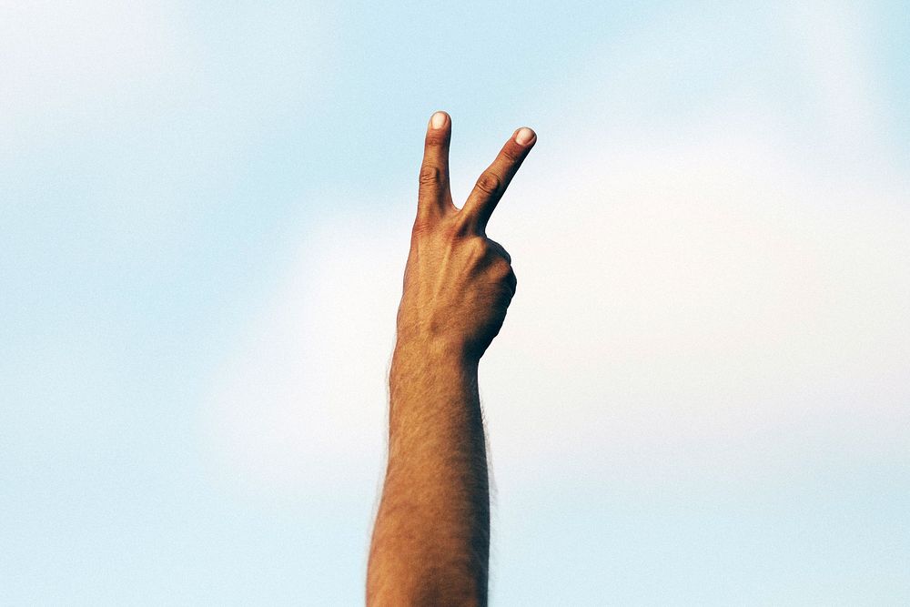 A hand with two fingers raised in a peace sign. Original public domain image from Wikimedia Commons