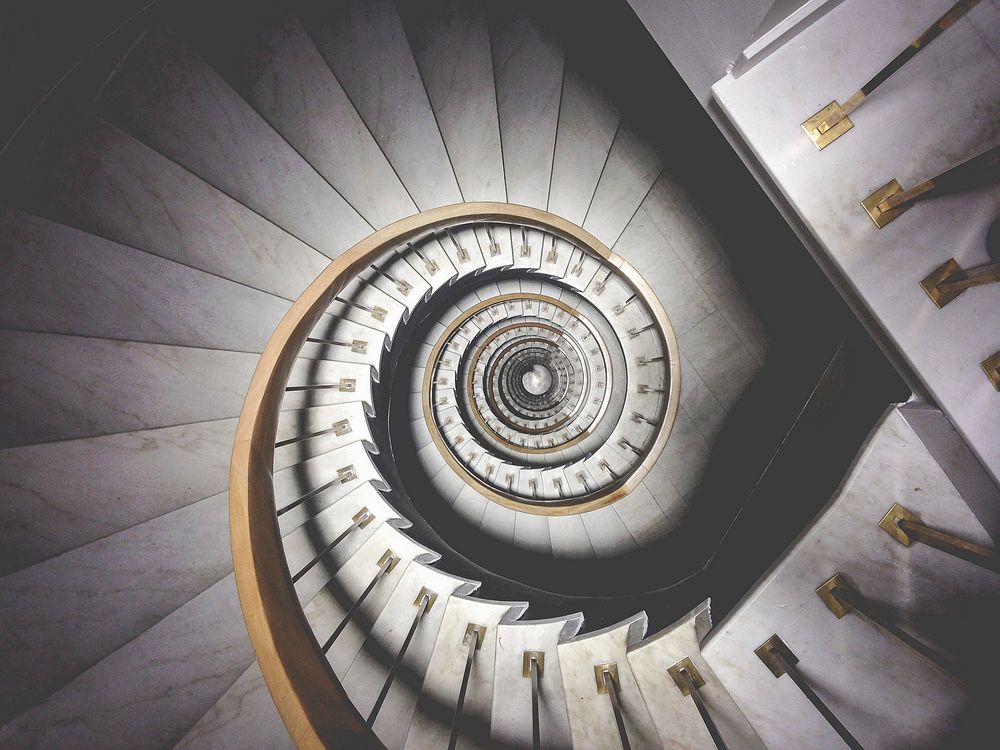 Impressive view down a stairwell with spiral marble stairs. Original public domain image from Wikimedia Commons