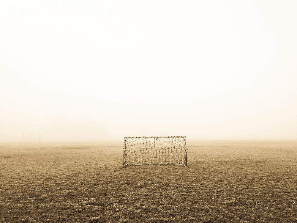 Soccer goal on brown field. Original public domain image from Wikimedia Commons