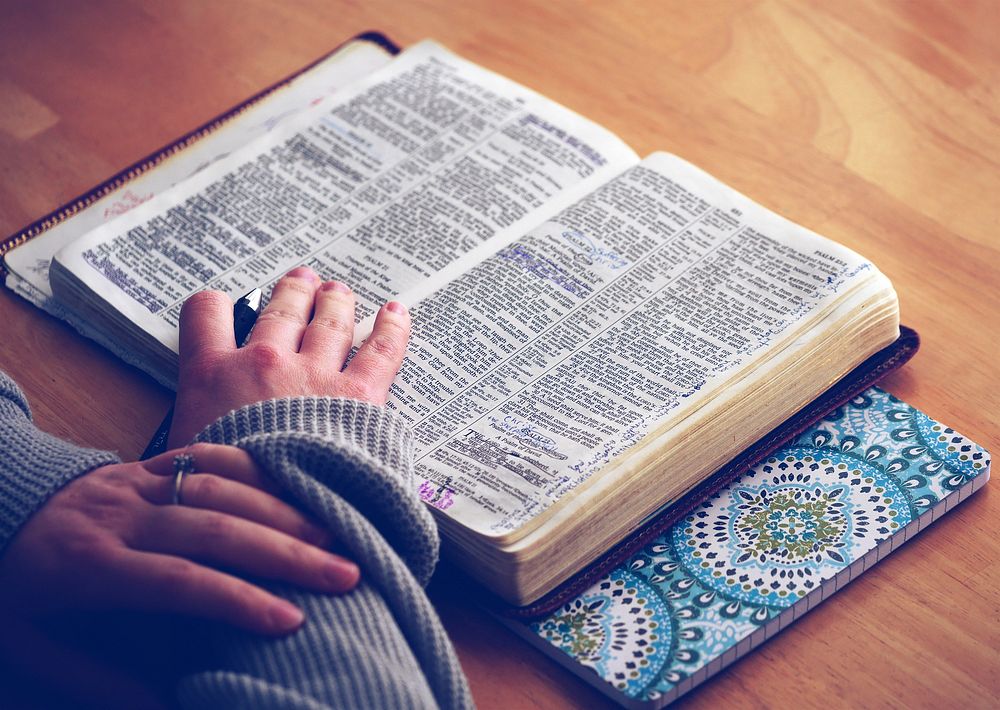 Woman reading the bible on the table. Original public domain image from Wikimedia Commons