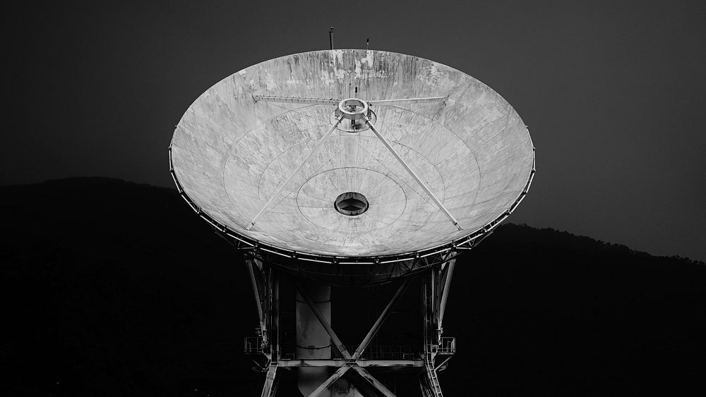 A black-and-white shot of a dish radio telescope. Original public domain image from Wikimedia Commons