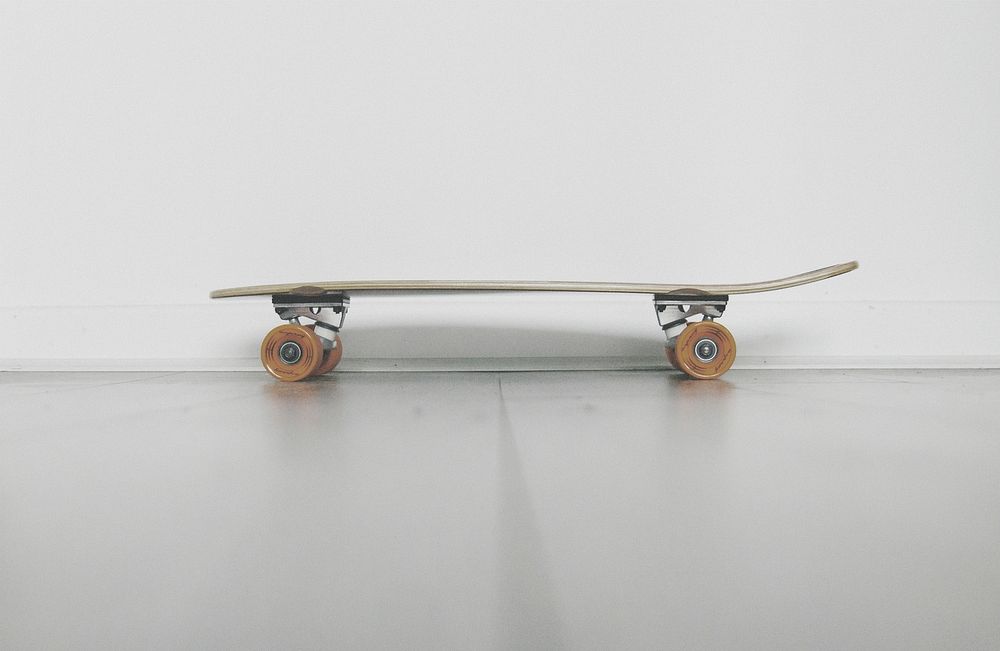 A low shot of a skateboard near a white wall. Original public domain image from Wikimedia Commons