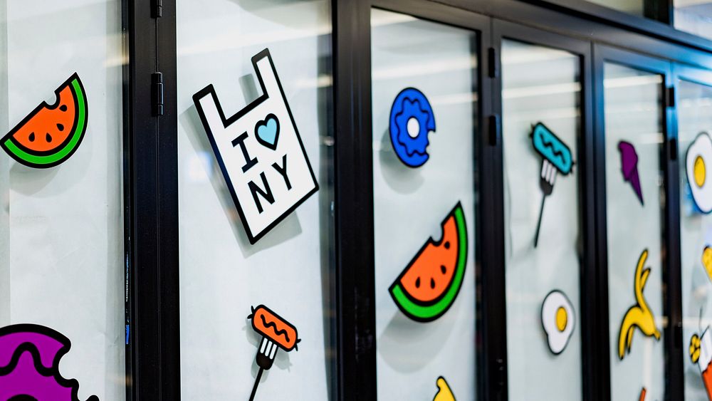 Windows with dark frames and cartoon fruit stickers in Columbus Circle. Original public domain image from Wikimedia Commons