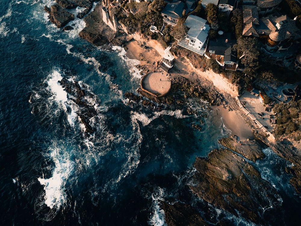 Drone aerial view of the rocky populated coast crashed by the waves at Laguna Beach. Original public domain image from…