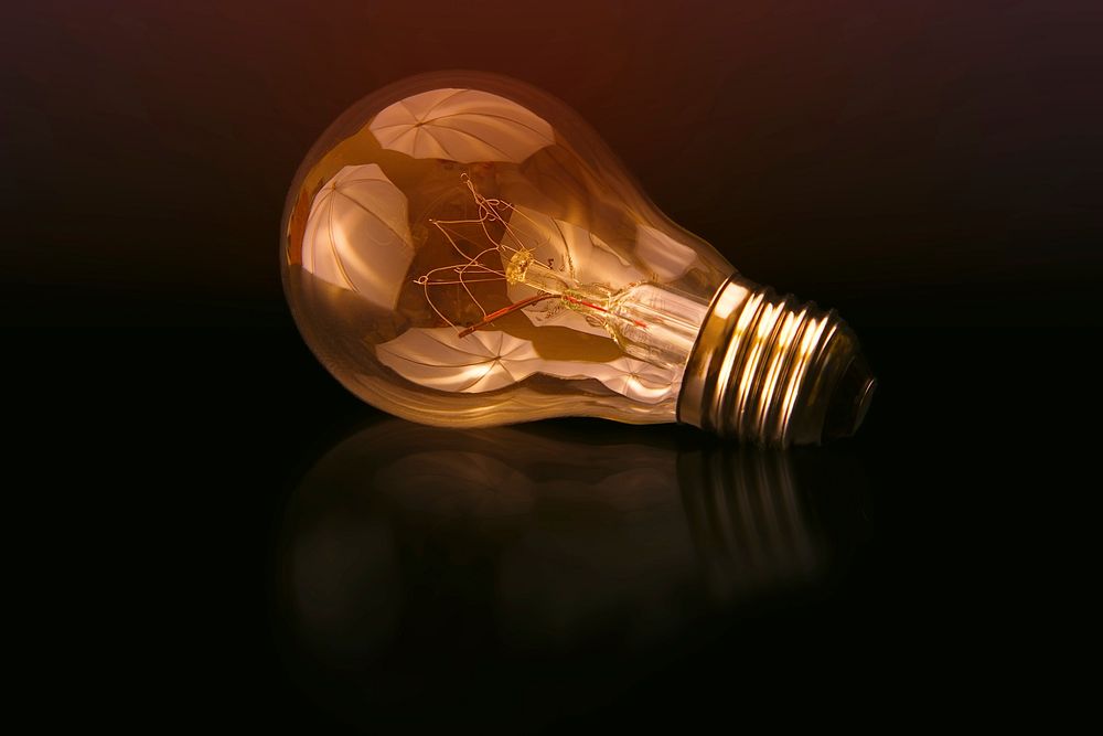 Incandescent bulb on black surface. Original public domain image from Wikimedia Commons