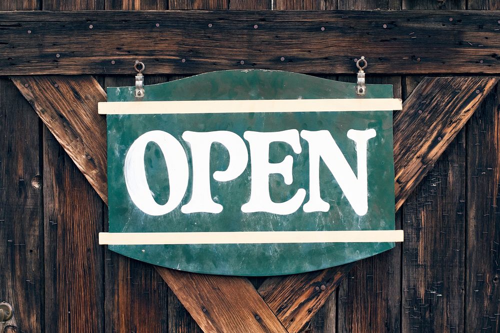 A large green “open” signboard on an old wooden door. Original public domain image from Wikimedia Commons