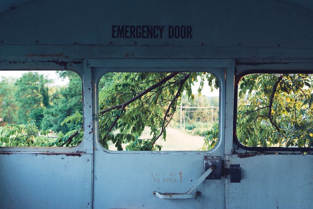 Looking out the window of the emergency exit door of an old school bus.. Original public domain image from Wikimedia Commons