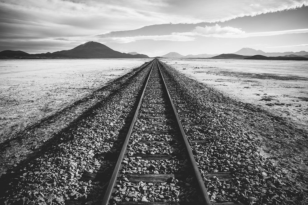 A black-and-white shot of a railway track through a barren wilderness in Bolivia. Original public domain image from…