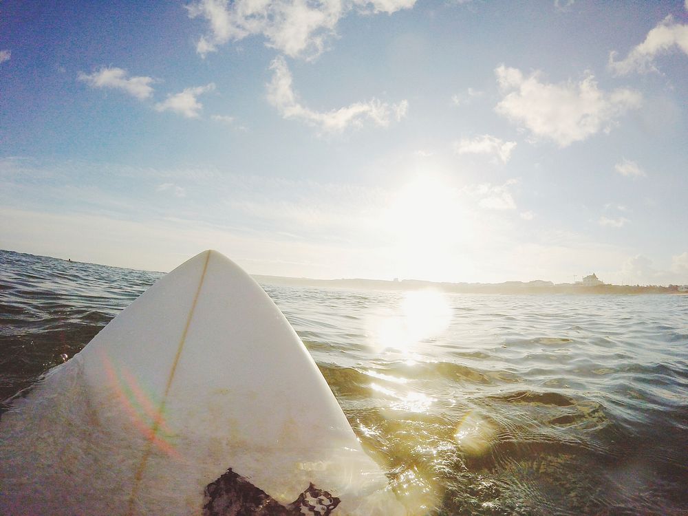 The front of a surfboard in the water facing the sun in Peniche. Original public domain image from Wikimedia Commons