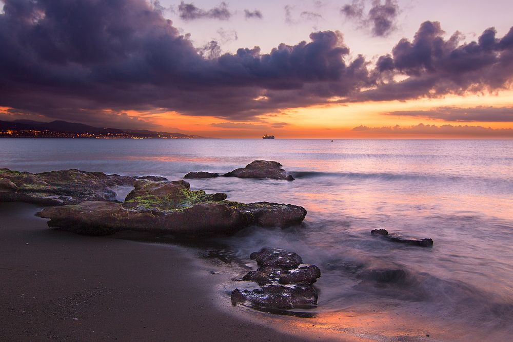 Purple sunset, rocky shoreline, sea. Original public domain image from Wikimedia Commons