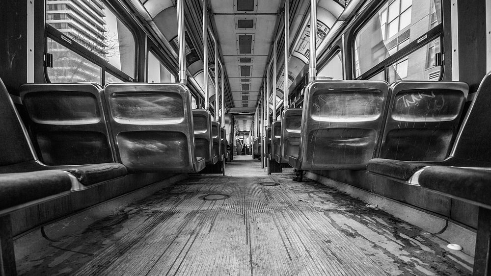 Black and white shot of carriage interior with dirty floor and seating. Original public domain image from Wikimedia Commons