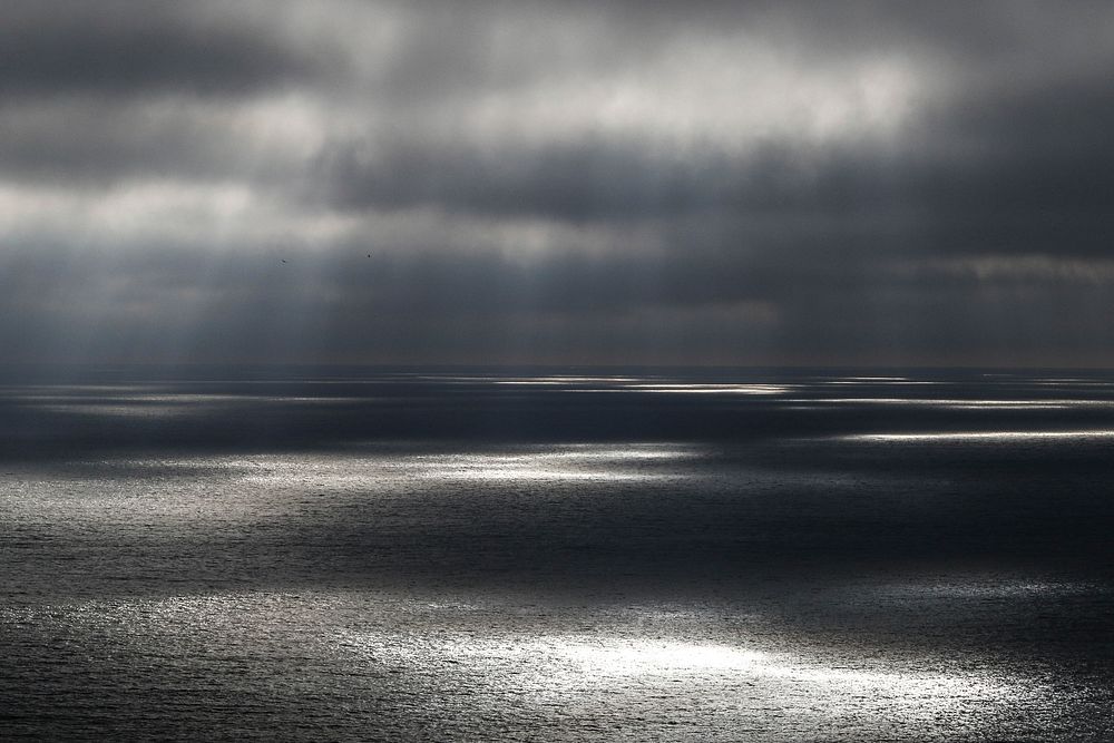 Sunlight through clouds over sea. Original public domain image from Wikimedia Commons