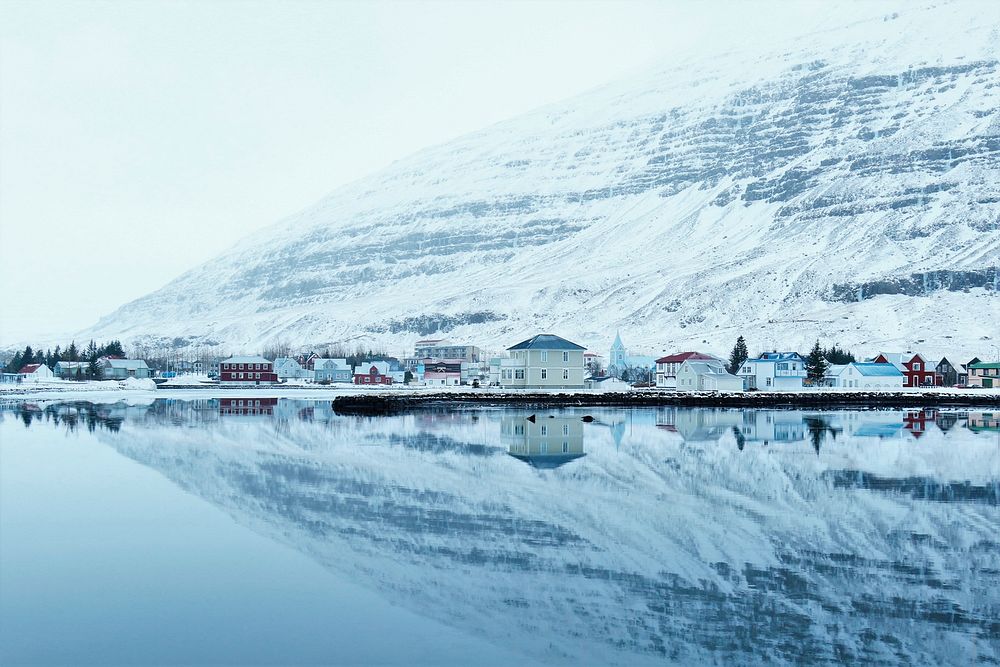A snowy village reflection in the water with a mountain view. Original public domain image from Wikimedia Commons