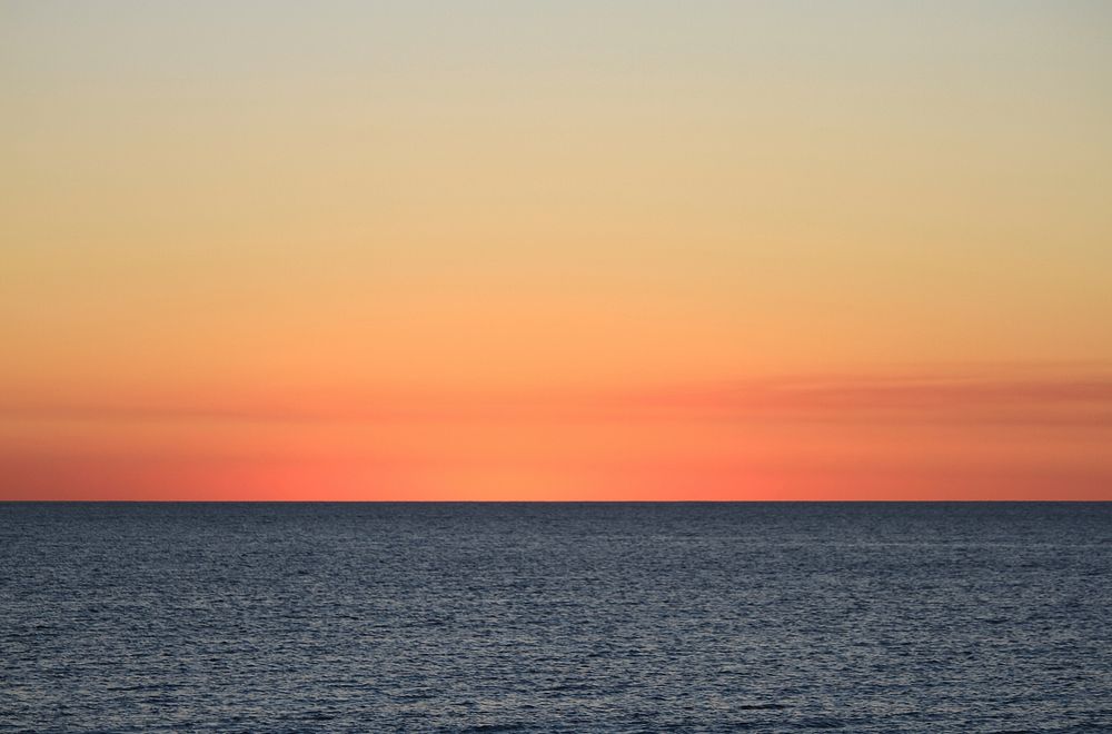 The golden sun resting on the horizon at sea in Fremantle, Australia. Original public domain image from Wikimedia Commons