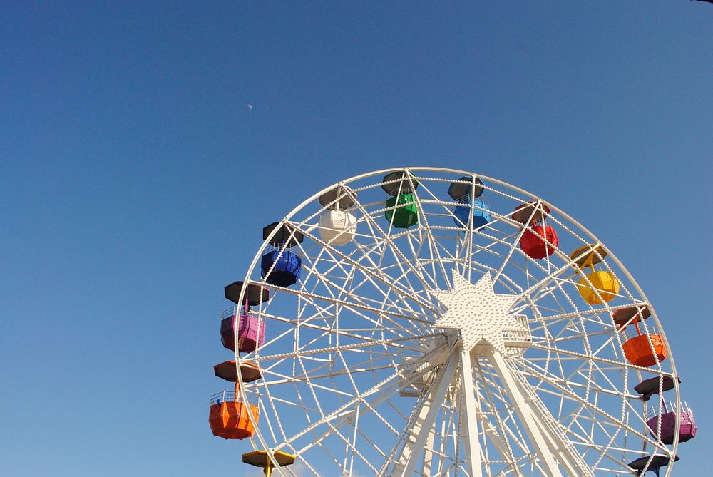 A white Ferris wheel with rainbow colored passenger cars in Tibidabo. Original public domain image from Wikimedia Commons