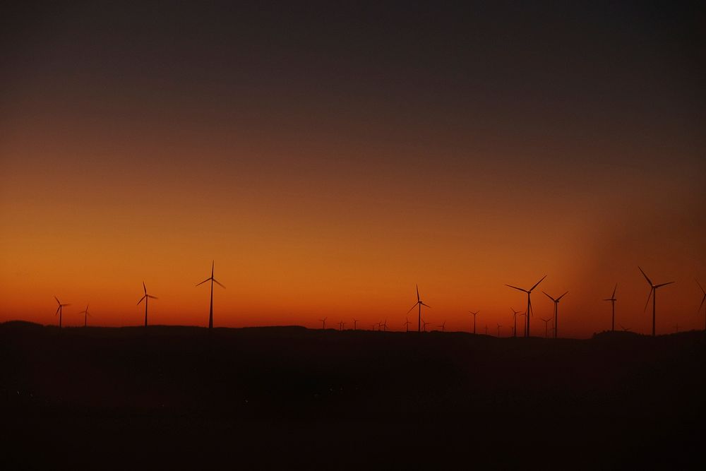 Wind turbine silhouettes at sunset against an orange and red sky in Belgium. Original public domain image from Wikimedia…
