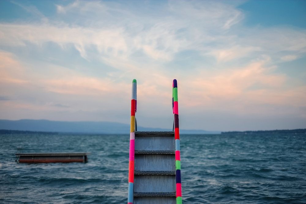 A striped, colored ladder staircase leading to the ocean water. Original public domain image from Wikimedia Commons