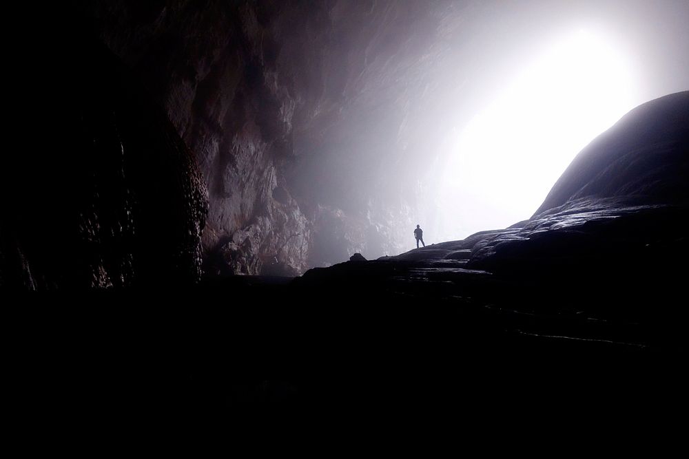 A silhouette of a man at the entrance to an enormous cavern. Original public domain image from Wikimedia Commons