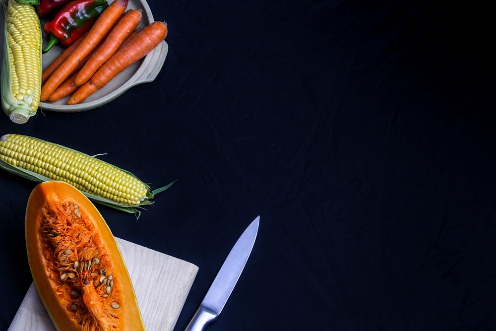 A flat lay shot of a knife, sweetcorns, pumpkins, carrots and various vegetables.. Original public domain image from…