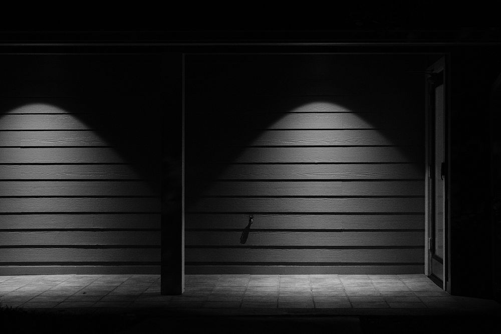 Black and white shot of wooden wall with light and shadow and door. Original public domain image from Wikimedia Commons