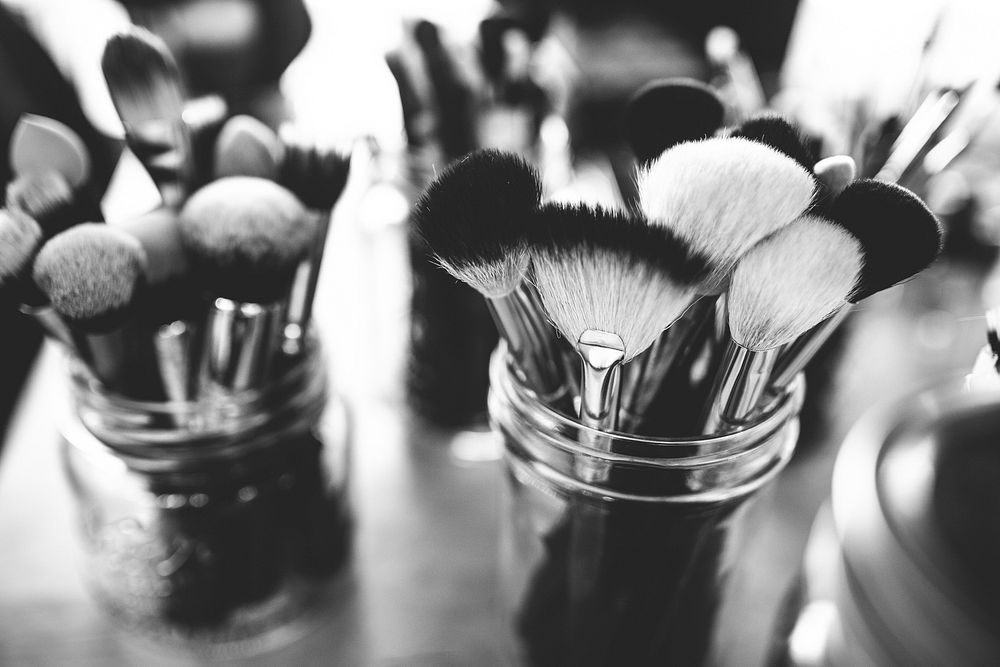 A black-and-white shot of make-up brushes in glass jars. Original public domain image from Wikimedia Commons