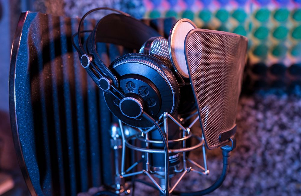 Professional studio headphones resting on a condenser microphone with a pop filter. Original public domain image from…