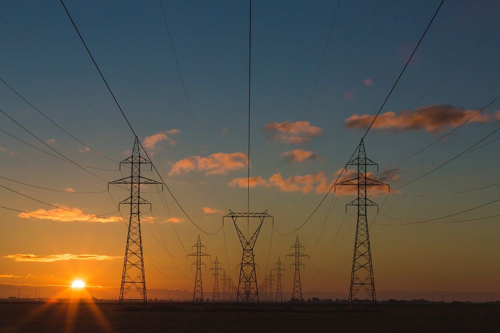 Electricity pylons at sunrise OR sunset, unidentified location. Original public domain image from Wikimedia Commons
