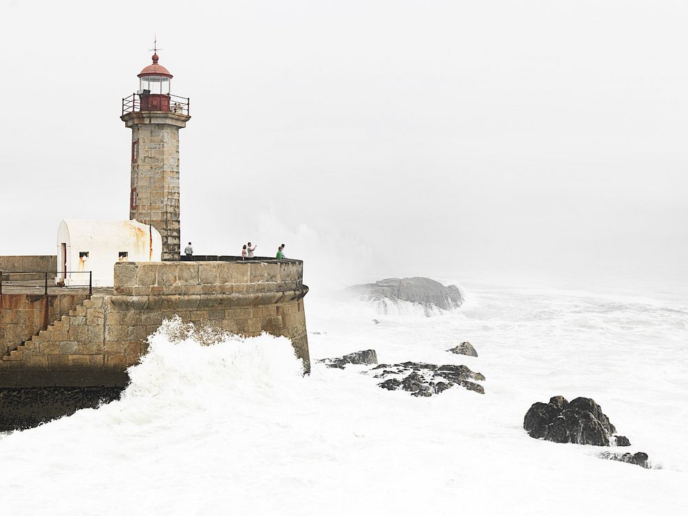 Lighthouse tower with big splashing of sea wave. Original public domain image from Wikimedia Commons