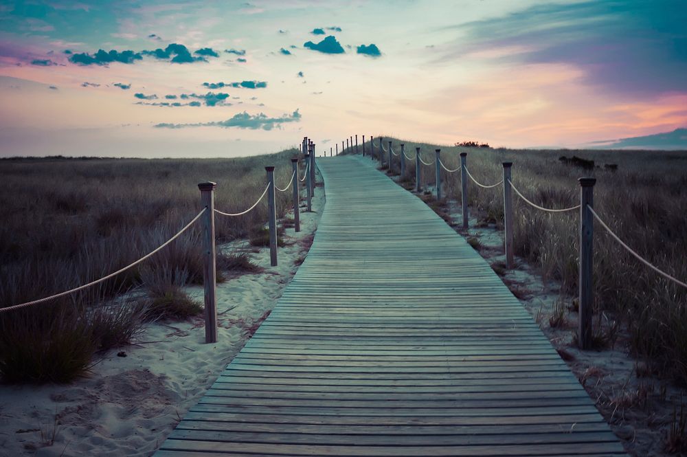 Wooden boardwalk with rope fence through the grass field after the sunset. Original public domain image from Wikimedia…