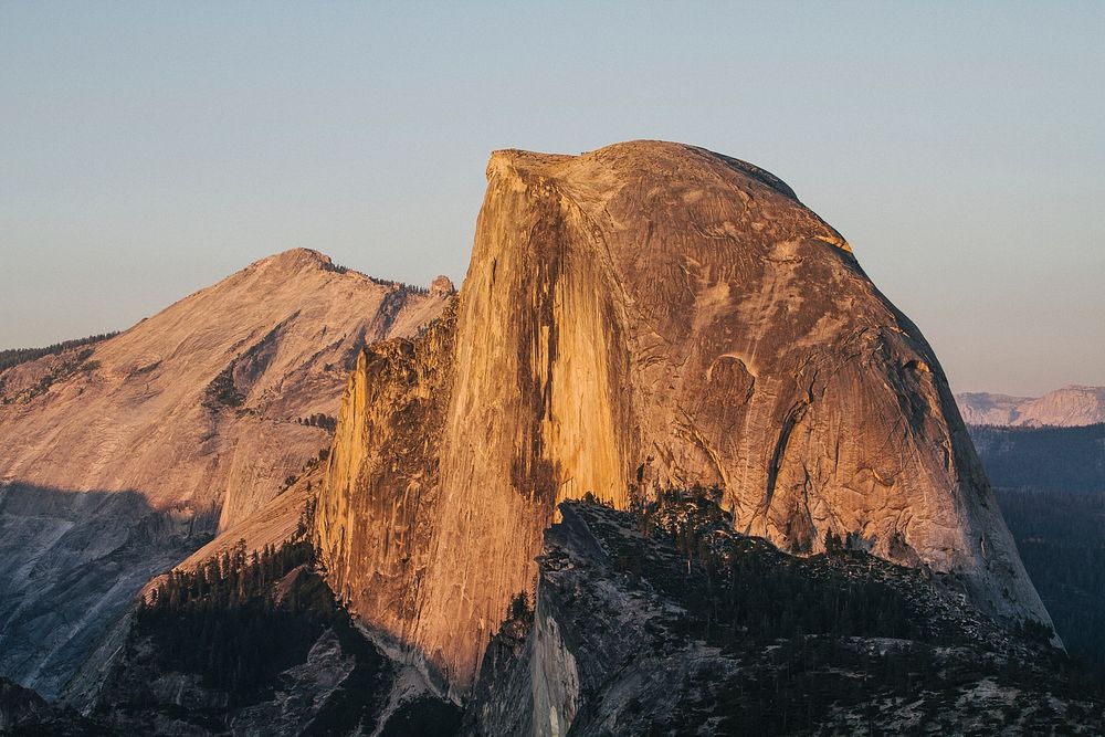 Rocky mountain cliffs of Half Dome at Yosemite National Park illuminated by sunset. Original public domain image from…