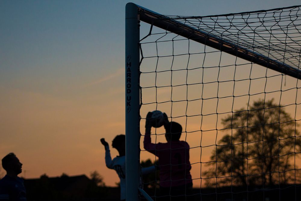 Three children play soccer at sunset at Ewen Fields. Original public domain image from Wikimedia Commons