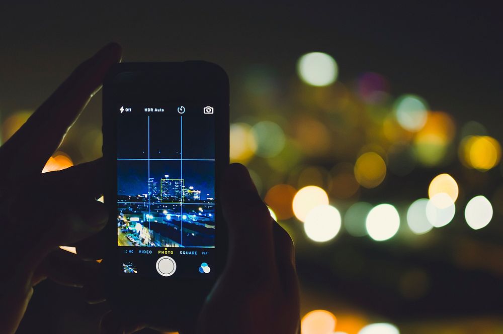 A photo of someone taking a photo of the skyline at night on an iPhone Cellphone. Original public domain image from…